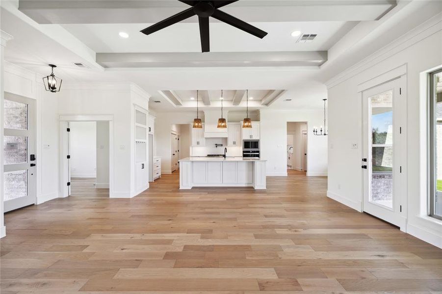 Unfurnished living room featuring ceiling fan with notable chandelier, light hardwood / wood-style floors, a raised ceiling, and sink