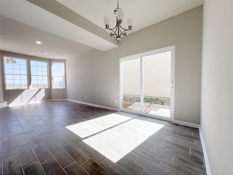 Unfurnished room with wood tiled floor, a chandelier, and plenty of natural light Unfurnished room with wood tiled floor, a chandelier, and plenty of natural light