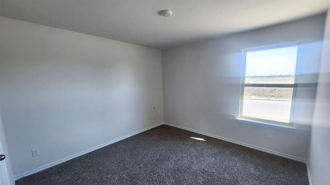 White walls showcasing a single window with a white frame, dark gray textured carpeting, and white baseboards