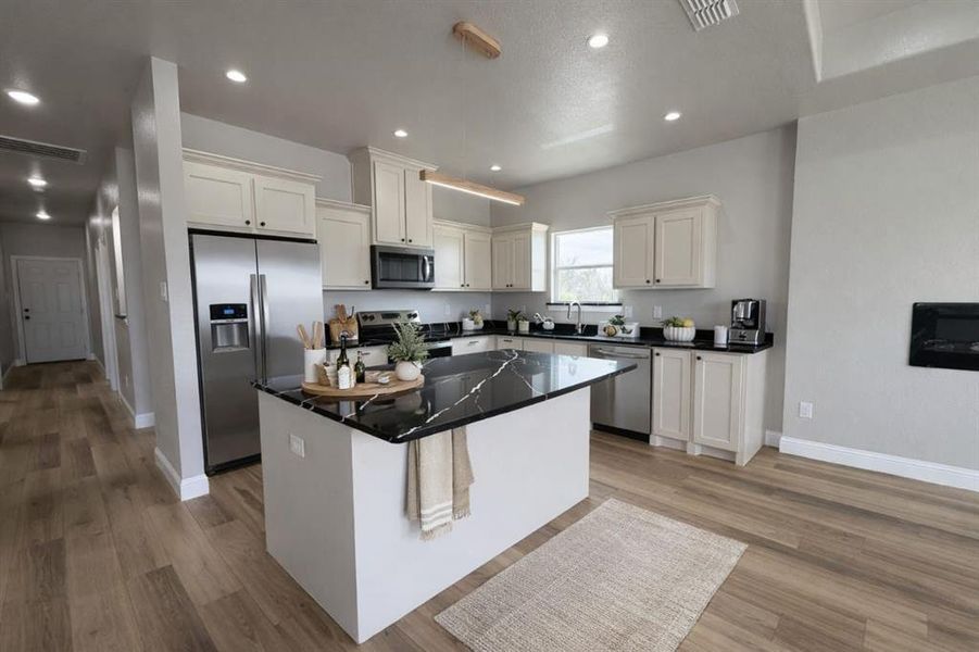 Kitchen with stainless steel appliances, a center island, light wood-style floors, white cabinetry, and recessed lighting