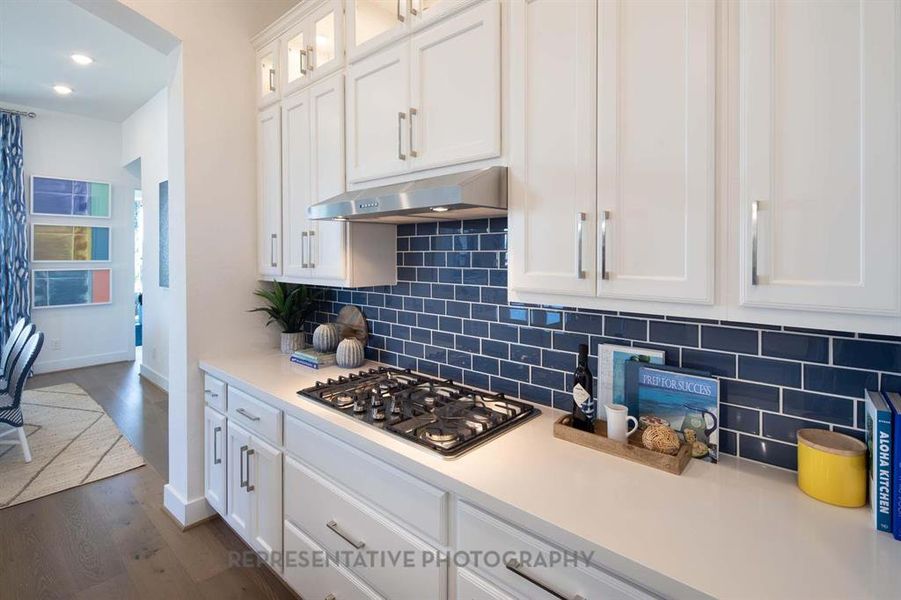 Kitchen featuring white cabinetry, dark wood-style flooring, backsplash, stainless steel gas cooktop, and recessed lighting Kitchen featuring white cabinetry, dark wood-style flooring, backsplash, stainless steel gas cooktop, and recessed lighting