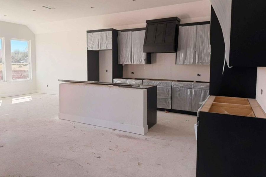 Kitchen with dark cabinetry, a kitchen island, and lofted ceiling