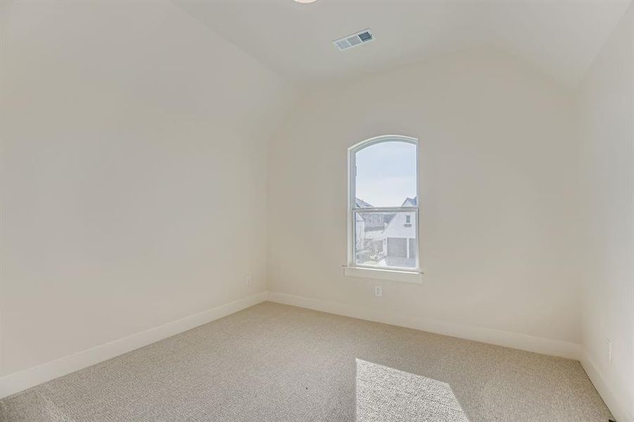 Carpeted empty room with vaulted ceiling