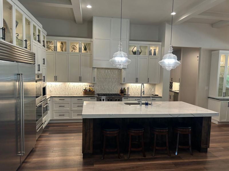 Kitchen featuring beamed ceiling, glass insert cabinets, appliances with stainless steel finishes, light stone counters, and white cabinets Kitchen featuring beamed ceiling, glass insert cabinets, appliances with stainless steel finishes, light stone counters, and white cabinets