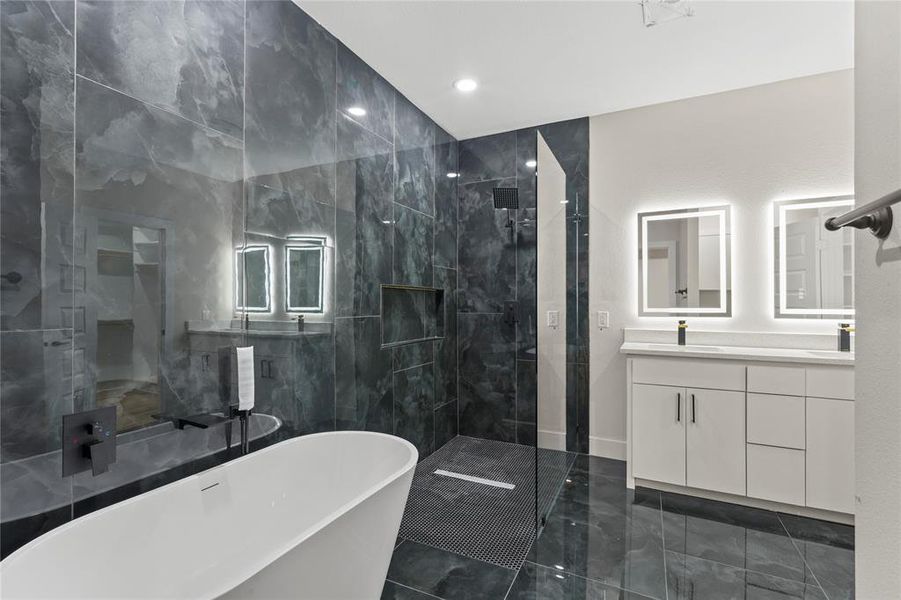 Bathroom featuring a freestanding bath, vanity, a marble finish shower, recessed lighting, and tile walls Bathroom featuring a freestanding bath, vanity, a marble finish shower, recessed lighting, and tile walls