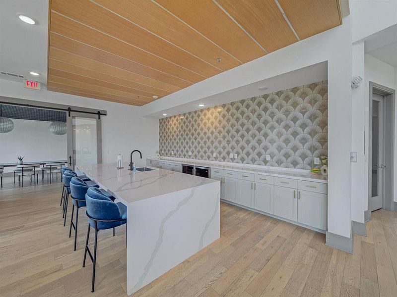 Kitchen with a center island with sink, light stone counters, recessed lighting, white cabinetry, and a barn door