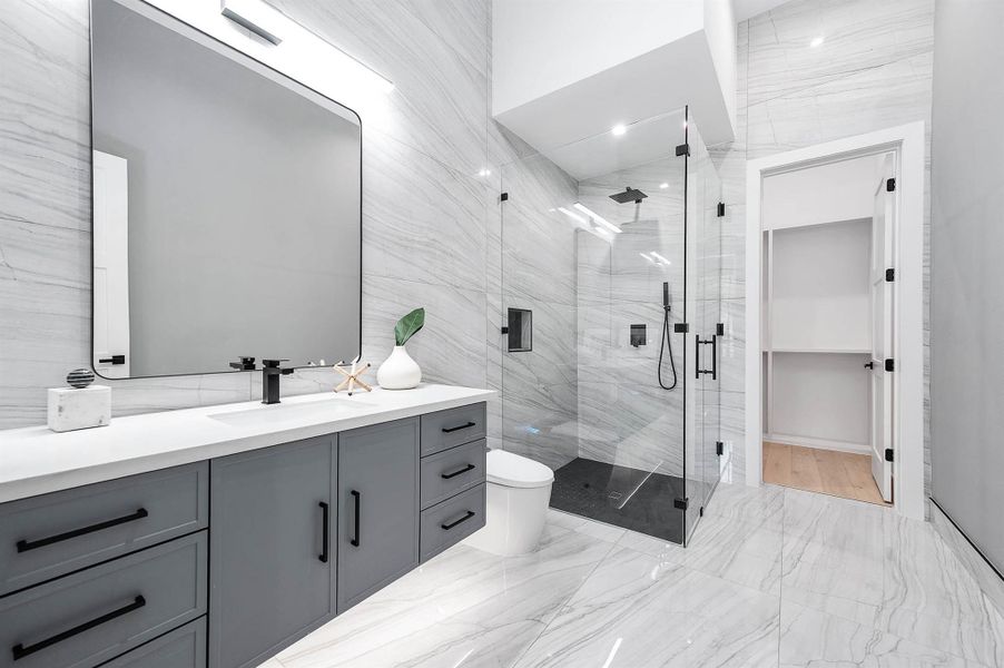 En suite bathroom with elegant floor-to-ceiling porcelain tile, creating a sleek and modern finish throughout the space.