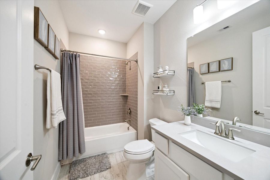 Beautifully finished secondary bath with a sleek subway tile surround, quartz vanity, and thoughtful storage.