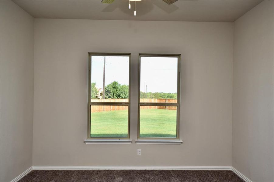 Empty room with dark colored carpet and ceiling fan