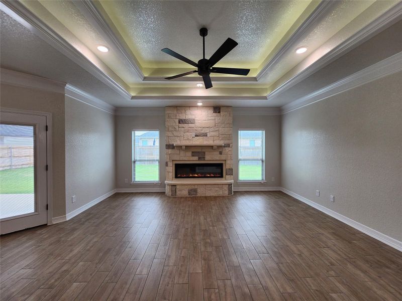 A refined living space showcasing a stone fireplace and elegant tray ceilings. A refined living space showcasing a stone fireplace and elegant tray ceilings.