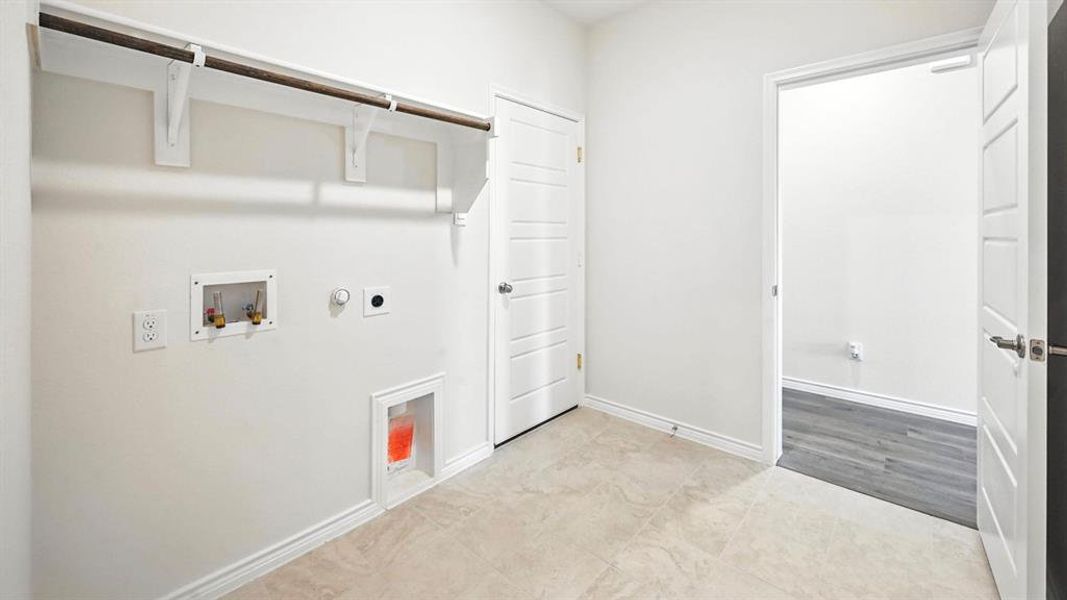 Dedicated utility space featuring a hanging rod and shelf, tile flooring, and a white paneled door