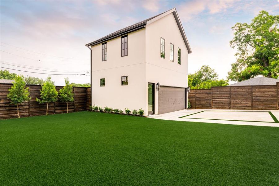 Back of house featuring stucco siding, concrete driveway, a fenced backyard, and a garage