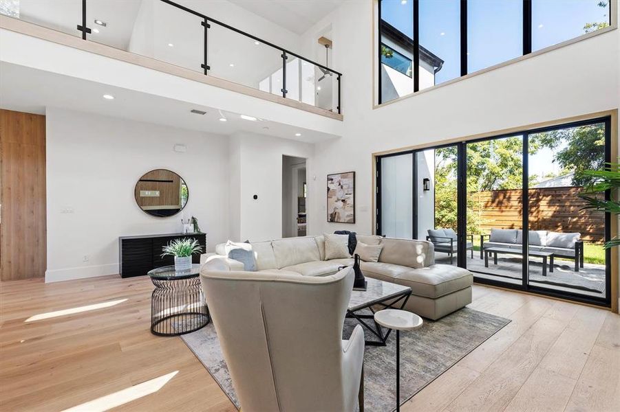 Living room with a towering ceiling and light hardwood / wood-style floors