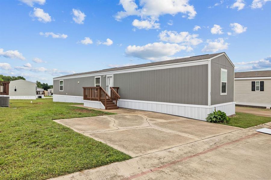 Single-story manufactured home featuring gray vertical siding and white trim Single-story manufactured home featuring gray vertical siding and white trim