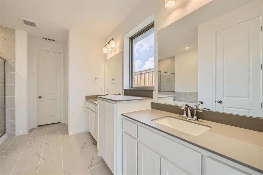 Bathroom featuring a shower with shower door, vanity, and tile floors