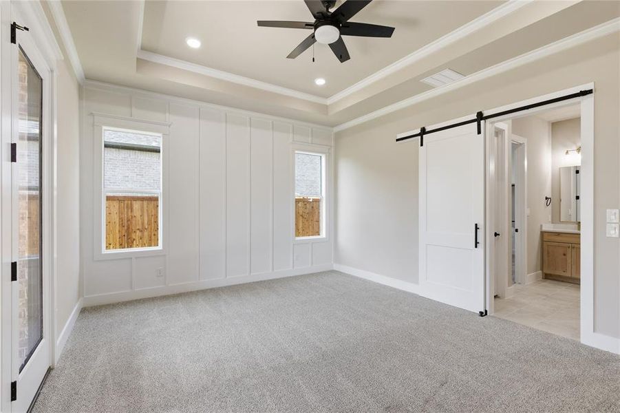 Spacious room featuring light gray carpeting and a tray ceiling with recessed lighting
