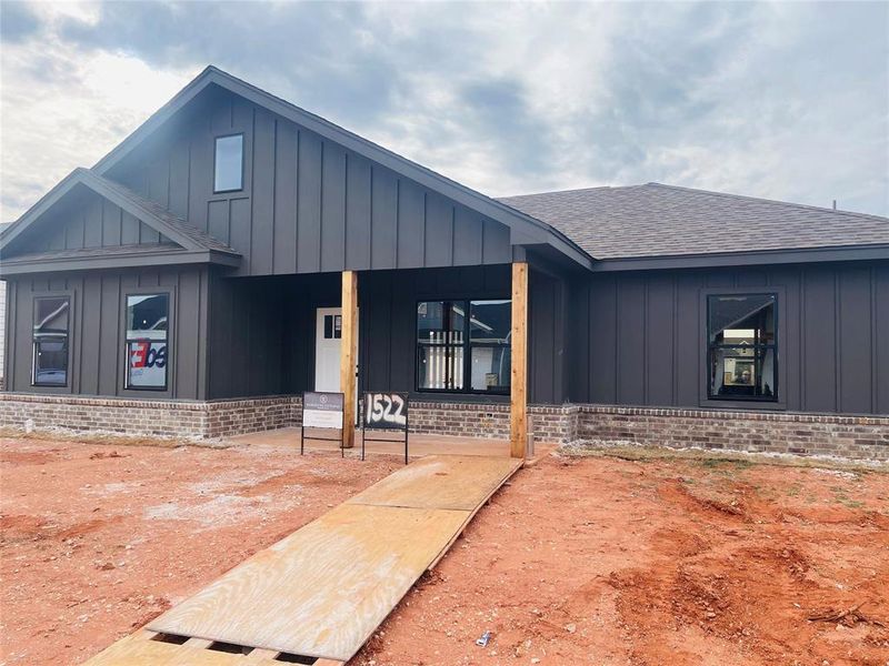 View of front of home with board and batten siding, roof with shingles, a porch, and brick siding View of front of home with board and batten siding, roof with shingles, a porch, and brick siding