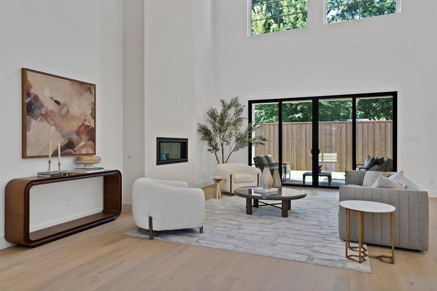 Spacious living area featuring high ceilings, light wood-finish flooring, and a modern built-in fireplace