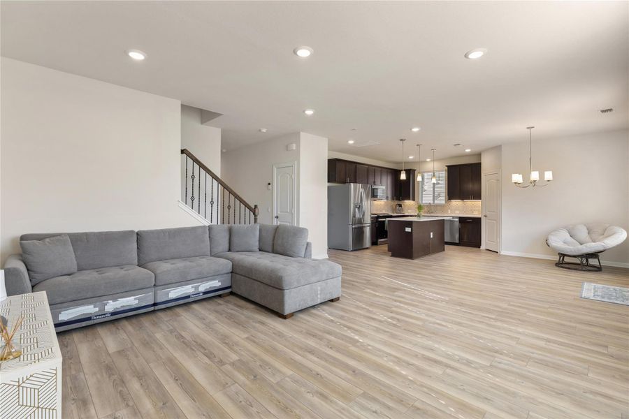 Living room with stairway, light wood-type flooring, recessed lighting, and a chandelier