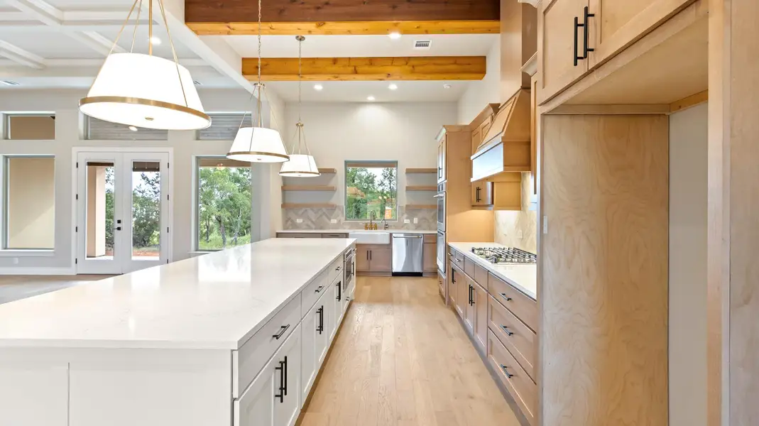 Kitchen with hanging light fixtures, light wood-type flooring, light stone counters, backsplash, and beamed ceiling