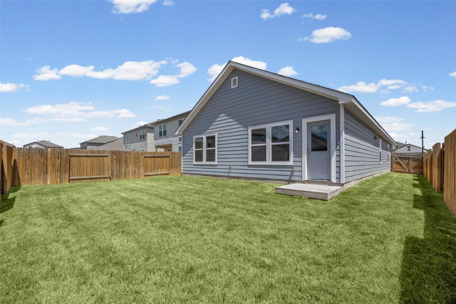 A wooden privacy fence surrounds the level green lawn behind this classic siding home. A wooden privacy fence surrounds the level green lawn behind this classic siding home.
