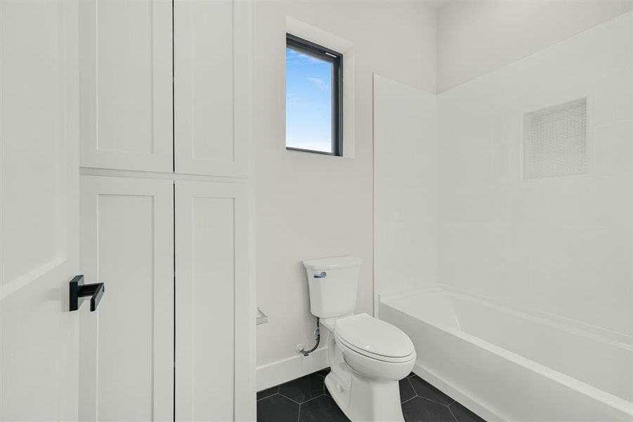 Bathroom featuring shower / bath combination, toilet, and tile patterned floors