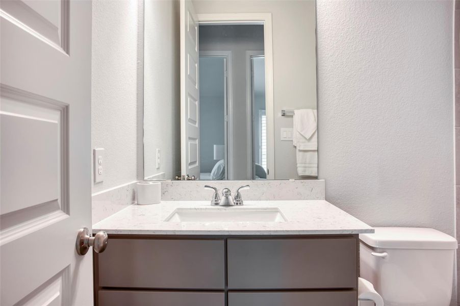 This bathroom features a modern vanity with a sleek marble countertop and an under-mount sink. It includes a large mirror, neutral wall color, and a convenient toilet, offering a clean and bright space. This bathroom features a modern vanity with a sleek marble countertop and an under-mount sink. It includes a large mirror, neutral wall color, and a convenient toilet, offering a clean and bright space.