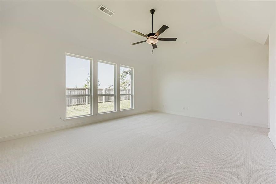 Empty room featuring light colored carpet, ceiling fan, and high vaulted ceiling