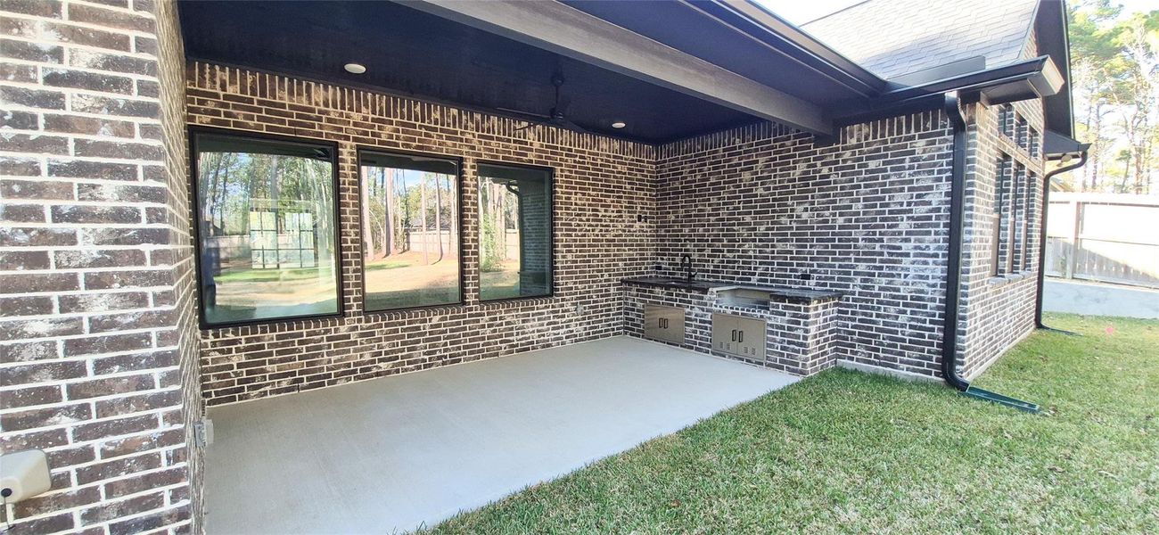 Covered Back Porch with Custom Trim Ceiling and Summer Kitchen Featuring a Gas Grill and Sink