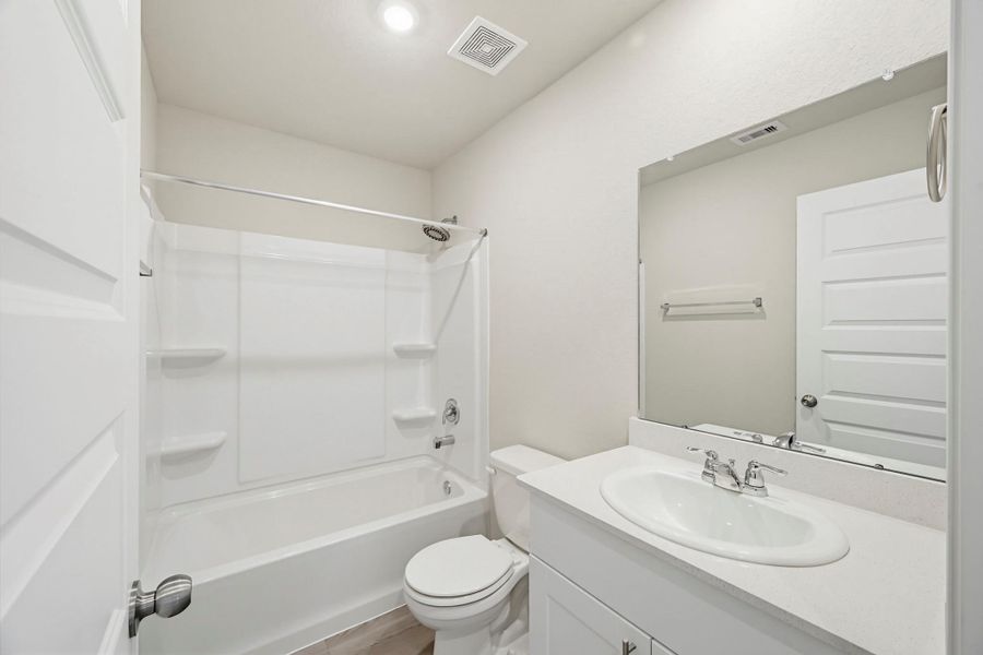 Bathroom #2. Tub and shower combo, clean white surround, and a Silestone vanity.