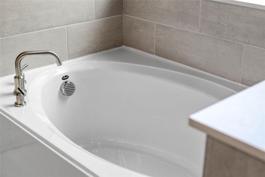 Indulge in the primary bath's deep, built-in soaking tub with elegant fixtures and a sleek tile surround for a true spa-like retreat.