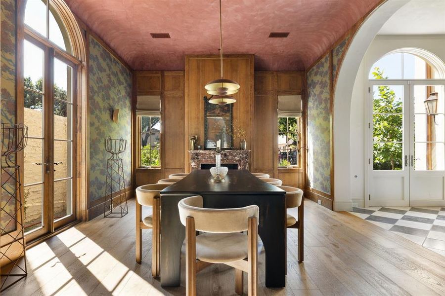 Dining room with healthy amount of natural light, light wood-style flooring, wallpapered walls, french doors, and arched walkways
