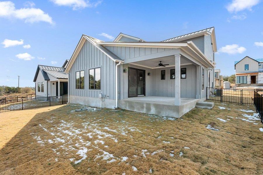 View of front of home with board and batten siding, ceiling fan, a standing seam roof, a metal roof, and a patio