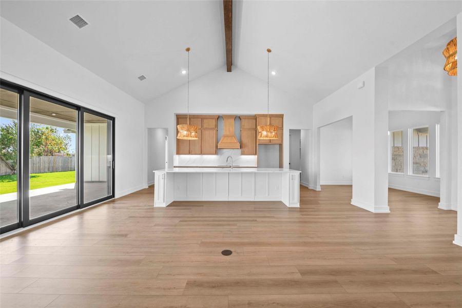 Unfurnished living room with high vaulted ceiling, beamed ceiling, light wood-type flooring, and recessed lighting Unfurnished living room with high vaulted ceiling, beamed ceiling, light wood-type flooring, and recessed lighting