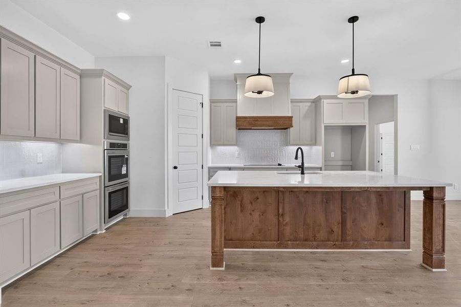 Expansive kitchen featuring a large wood-finish island with a light-toned countertop, complete with an undermount sink and matte black faucet Expansive kitchen featuring a large wood-finish island with a light-toned countertop, complete with an undermount sink and matte black faucet