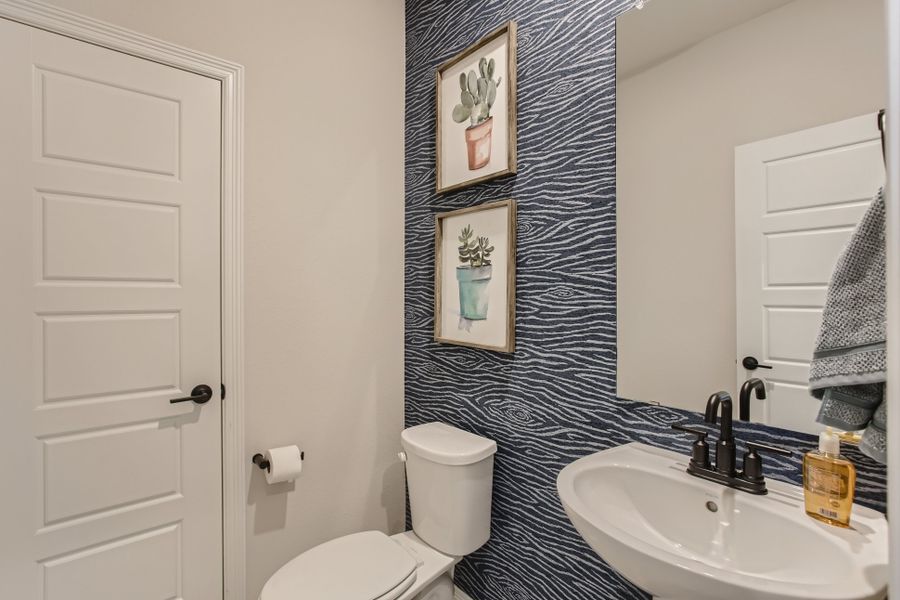 A bathroom with a sink toilet and a mirror.