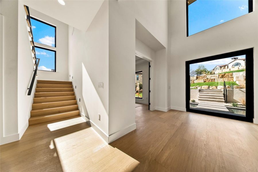 Entryway featuring a high ceiling, light wood-style flooring, and healthy amount of natural light Entryway featuring a high ceiling, light wood-style flooring, and healthy amount of natural light