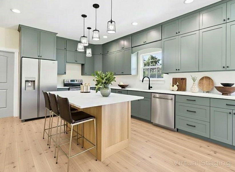 After photoKitchen with appliances with stainless steel finishes, hanging light fixtures, a kitchen bar, a kitchen island, and light wood finished floors