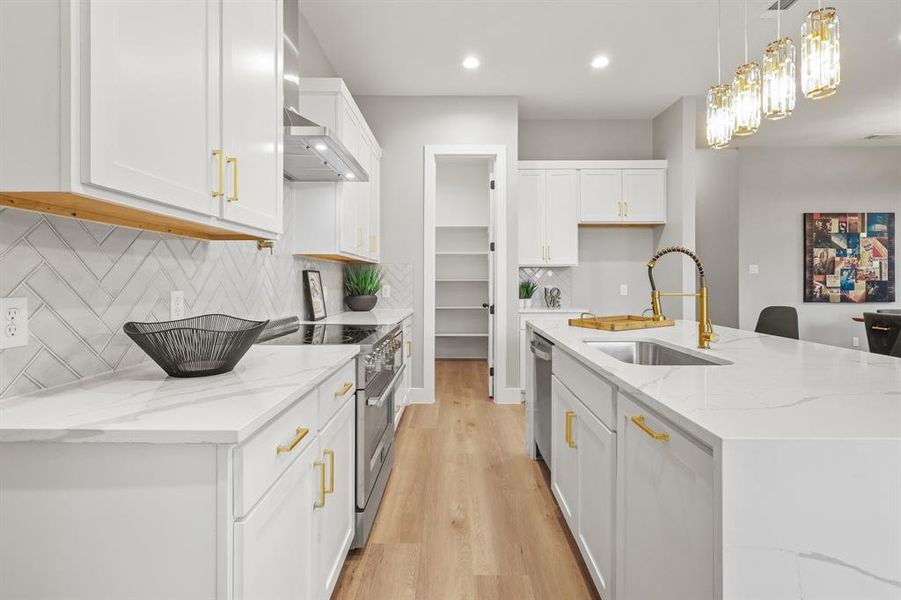 Kitchen featuring pendant lighting, sink, a kitchen island with sink, and white cabinets