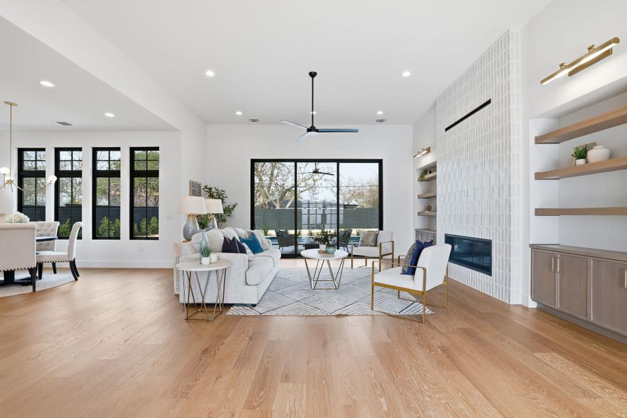 Living area with built in features, healthy amount of natural light, light wood-type flooring, ceiling fan, and recessed lighting