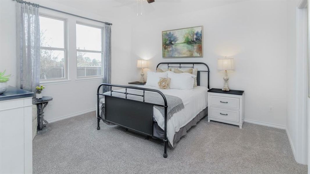 Bedroom featuring neutral carpeting, white walls, and a ceiling fan