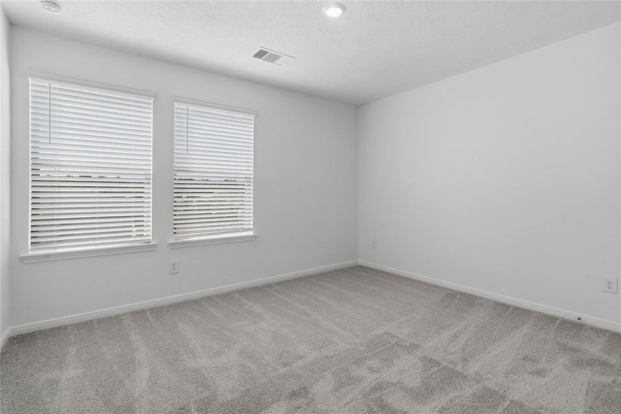 This secondary bedroom combines comfort and style, featuring plush carpeting, neutral paint, recessed lighting, large windows with blinds, and a spacious closet. This secondary bedroom combines comfort and style, featuring plush carpeting, neutral paint, recessed lighting, large windows with blinds, and a spacious closet.