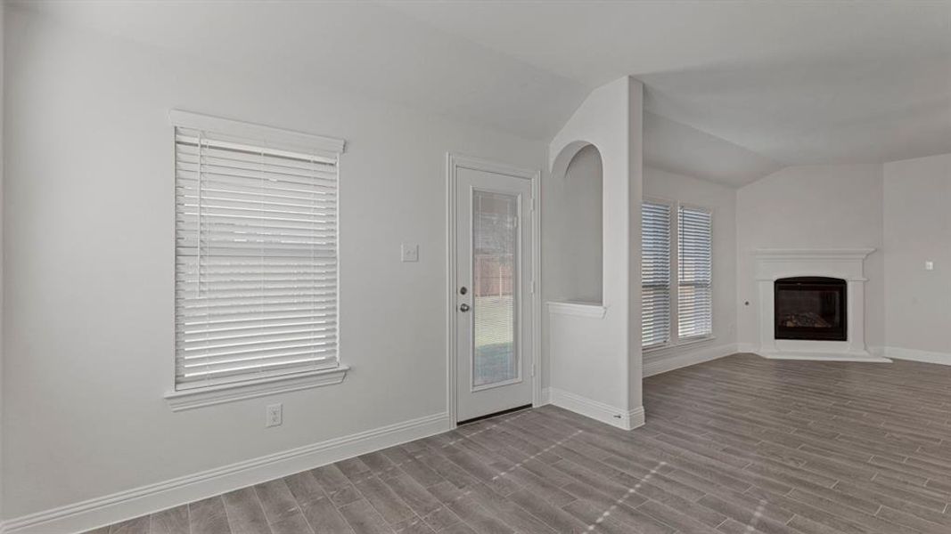 Unfurnished living room with lofted ceiling, a glass covered fireplace, and wood finish floors