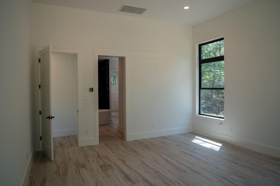 Primary bedroom features 12-foot ceilings and the abundance of natural light provided by the large windows, creating a spacious and inviting atmosphere.