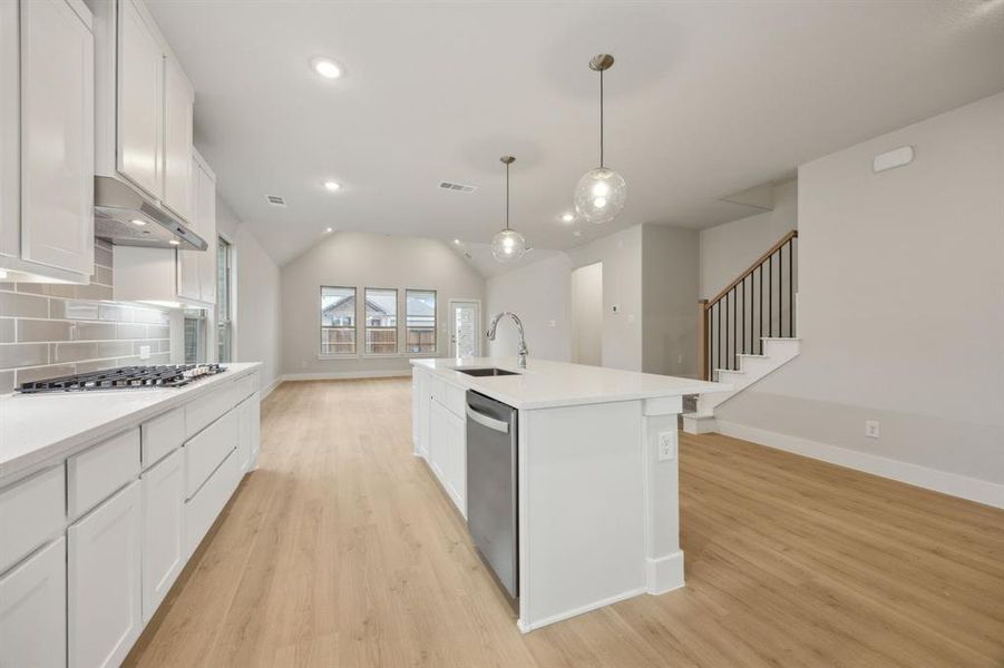 Kitchen with appliances with stainless steel finishes, pendant lighting, white cabinetry, an island with sink, and sink