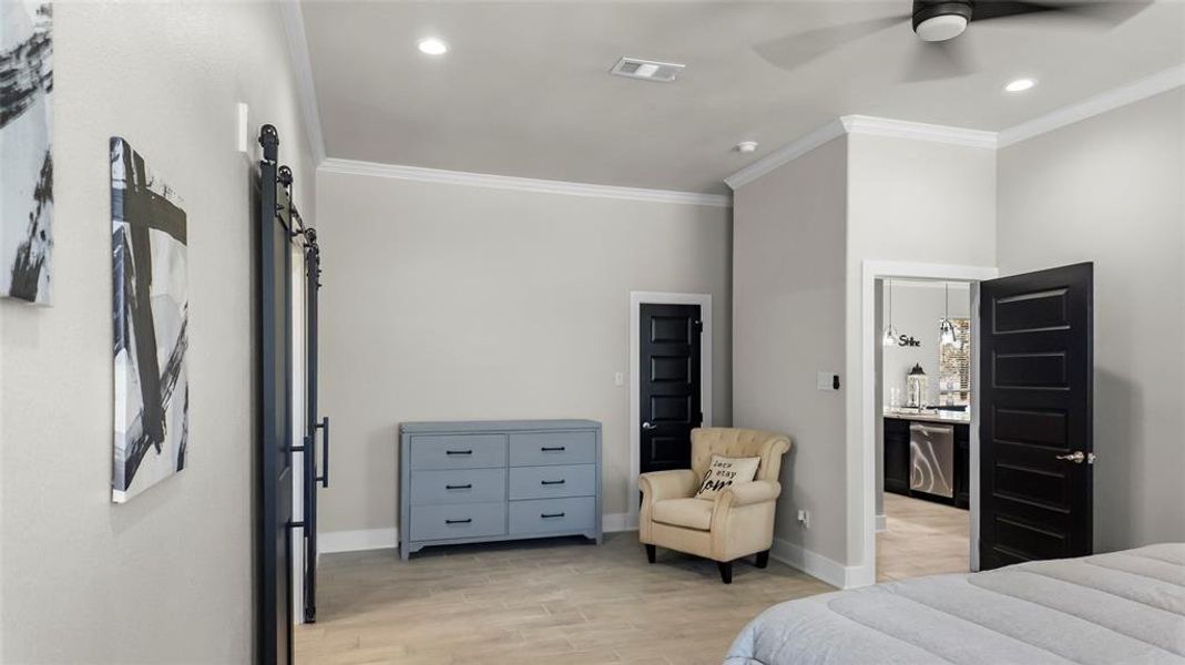 Bedroom featuring crown molding, light wood finished floors, a barn door, ceiling fan, and recessed lighting