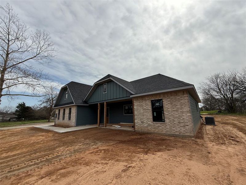 View of front of home featuring brick siding, central AC unit, and a shingled roof