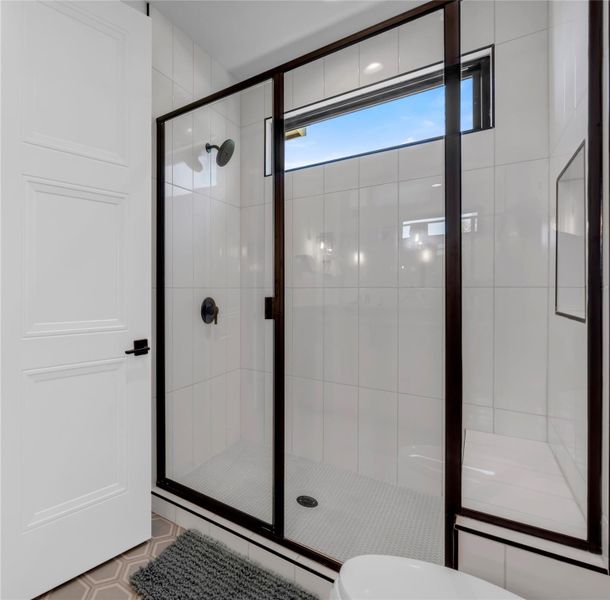 Bathroom four: Walk-in shower with dark-framed glass enclosure, white subway tile walls, and a built-in bench