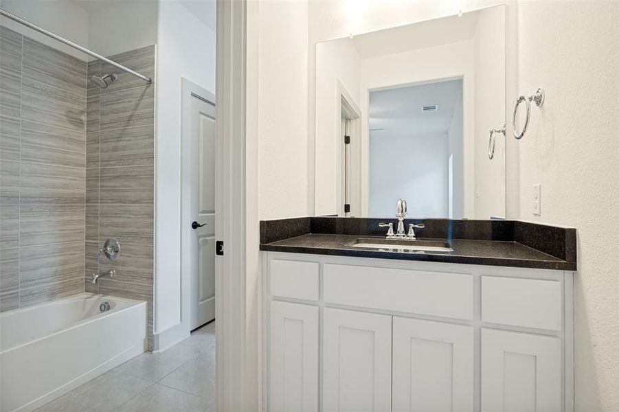 Bathroom vanity featuring white cabinetry, a dark countertop, and a rectangular undermount sink with chrome fixtures Bathroom vanity featuring white cabinetry, a dark countertop, and a rectangular undermount sink with chrome fixtures