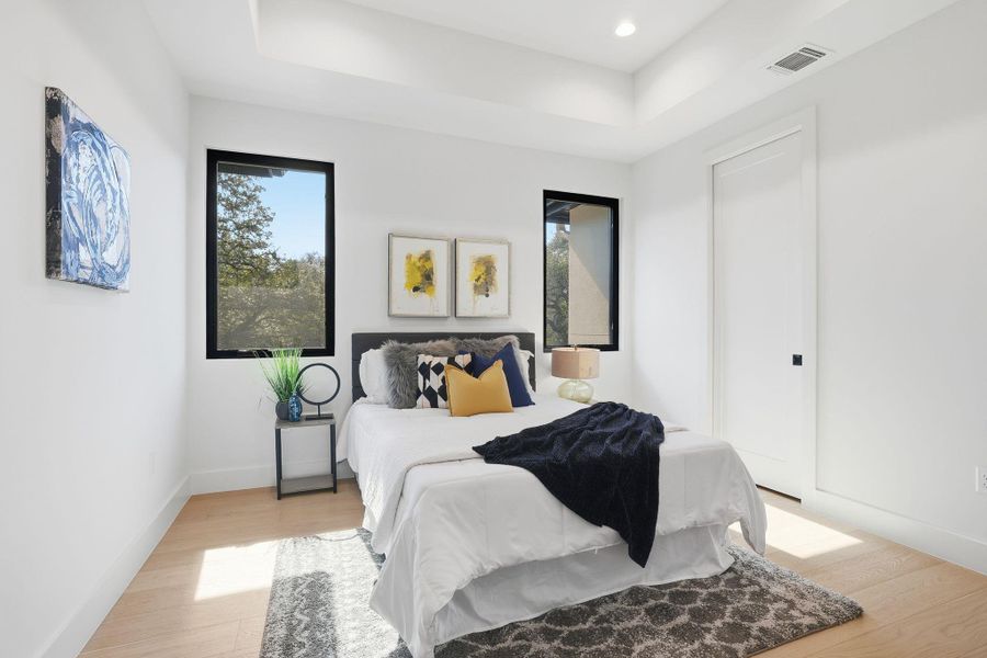Bedroom featuring light wood-style floors, a raised ceiling, and recessed lighting